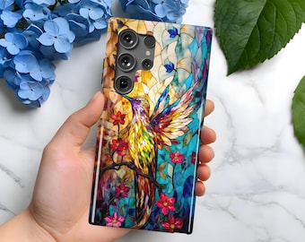 May include: A colourful phone case with a stained glass design featuring a hummingbird with outstretched wings and flowers. The case has a black camera bump with four lenses.