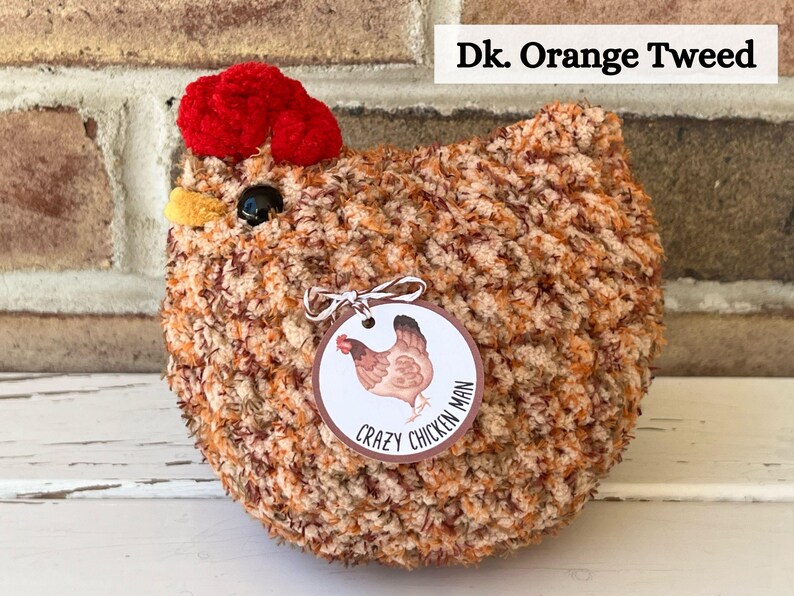 Puede incluir: Un juguete de peluche de pollo tejido a crochet con una cresta roja y un cuerpo de tweed marr&oacute;n y naranja. El juguete tiene una etiqueta que dice "Crazy Chicken Man".
