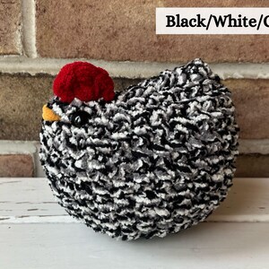 Puede incluir: Juguete de pollo de peluche negro, blanco y gris con una cresta roja. El pollo est&aacute; sentado sobre una superficie blanca.