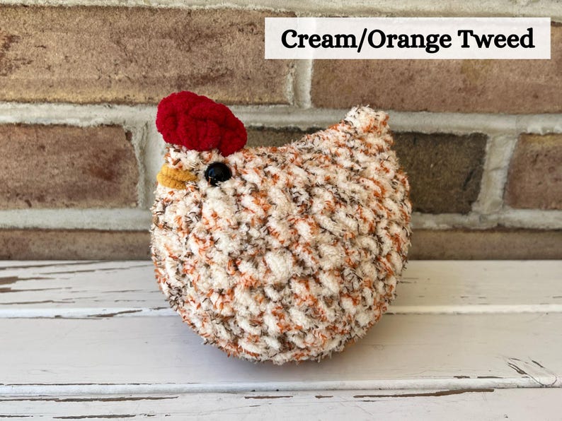Puede incluir: Pollo de crochet de tweed crema y naranja con cresta roja y pico amarillo.