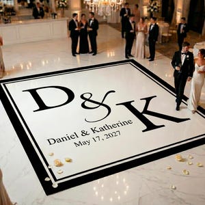 May include: A large square white dance floor decal featuring a thick black border and the black monogram D&K in the centre. Below the monogram, the text reads Daniel & Katherine and the date May 17, 2027, in a clean black serif font.