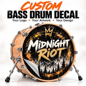 Op de afbeelding: Een bassdrum met een lichte houten ketel en metalen hardware, voorzien van een aangepaste ronde sticker. De sticker toont de tekst Midnight Riot in wit en goud, een kroonpictogram, een bergketen, dennenbomen en oranje verfspatten als accenten.