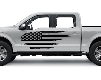 Könnte beinhalten: Ein silberner Pickup mit einem schwarzen, abgenutzten Aufkleber mit der amerikanischen Flagge an der Seite.