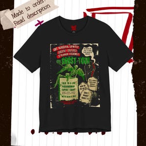 Puede incluir: Camiseta negra con un gráfico retro de "Ghost Tour". El diseño incluye un esqueleto y texto como "Got Vengeful Spirits?" y "Talk to a Live Paranormal Expert Today". La camiseta tiene un aspecto vintage.