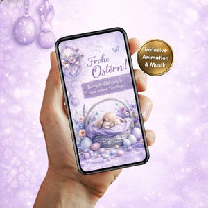 Op de afbeelding: Een smartphone toont een digitale paasgroet met een slapend konijn in een mand, eieren en bloemaccenten. De tekst luidt "Frohe Ostern!" en "Herzliche Ostergrüße und schöne Feiertage!" in een zacht paars kleurenschema. Een gouden munt met tekst is ook zichtbaar.