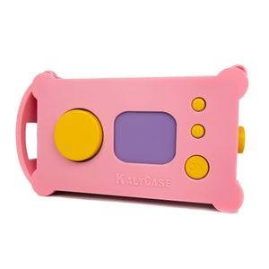 Puede incluir: Funda rosa para cámara con botones amarillos y pantalla morada. La funda tiene el texto "KALYCASE" impreso. La funda tiene un diseño redondeado con un asa lateral.