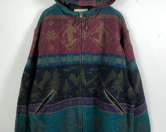 May include: A hooded jacket with a colorful geometric pattern. The jacket features a full zipper, two front pockets, and a hood. The color scheme includes burgundy, teal, navy, and brown. The jacket has a vintage, outdoorsy aesthetic.