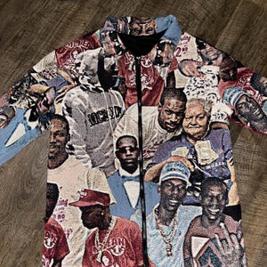 May include: A tapestry jacket featuring a collage of images of people in various poses. The jacket has a black zipper and a light blue collar. The images are in shades of red, white, black, and blue.
