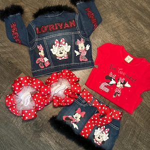 Puede incluir: Un conjunto de chaqueta vaquera, falda y camiseta roja con diseños de Minnie Mouse. La chaqueta y la falda tienen ribetes de piel sintética negra. La chaqueta tiene el nombre "LORIYAN" en la espalda. La camiseta dice "I'm Toodles!" y el conjunto incluye lazos de lunares rojos y blancos.