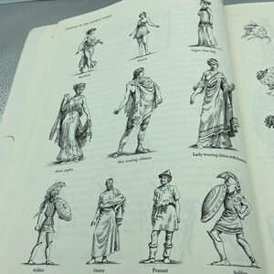 May include: An open book page featuring black and white illustrations of ancient world costumes. The illustrations include figures labeled as a dancer, upper-class lady, man wearing chlamys, lady wearing chiton, soldier, orator, and peasant.