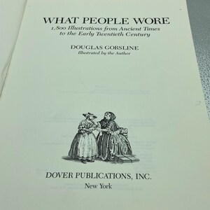May include: Open book page with the title "WHAT PEOPLE WORE" and the subtitle "1,800 Illustrations from Ancient Times to the Early Twentieth Century." The author is Douglas Gorsline. A black and white illustration of two women in historical clothing is at the bottom.