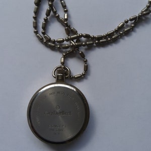 May include: Silver pocket watch with a chain. The back of the watch has the text "Mary Engelbreit" and "Concept in Time NY".
