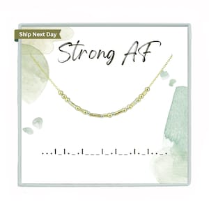 May include: Gold and silver beaded necklace with the text "Strong AF" on a white background with green watercolor accents.