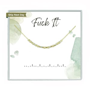 Peut inclure: Un collier doré avec un motif en code Morse est présenté sur une carte blanche. La carte porte les mots "Fuck It" en écriture cursive et des accents aquarelle. Le code Morse épelle la même phrase.