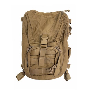 May include: Tan-colored tactical backpack with multiple compartments and straps. Features a front pocket with horizontal webbing, a central buckle closure, and adjustable shoulder straps. The backpack is designed for outdoor activities and carrying gear.