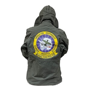 May include: A dark green hooded jacket with a large patch on the back. The patch is yellow and blue with the words "Operation Deepfreeze" and "Antarcticdevron Six".