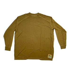 May include: A long-sleeved, olive drab shirt with a crew neck. The shirt has a small patch on the lower right side. The stitching is visible along the shoulders and sleeves. The shirt is made of a lightweight material.