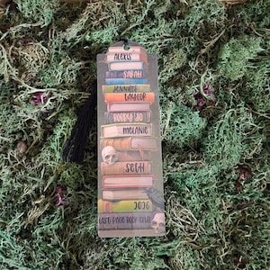 May include: A rectangular bookmark featuring a stack of colourful books with names Alexis, Sarah, Jennifer, Taylor, Bobby Jo, Melanie, and Seth printed on the spines. It includes a small skull, a raven, and the text 2026 Last Page Book Club.