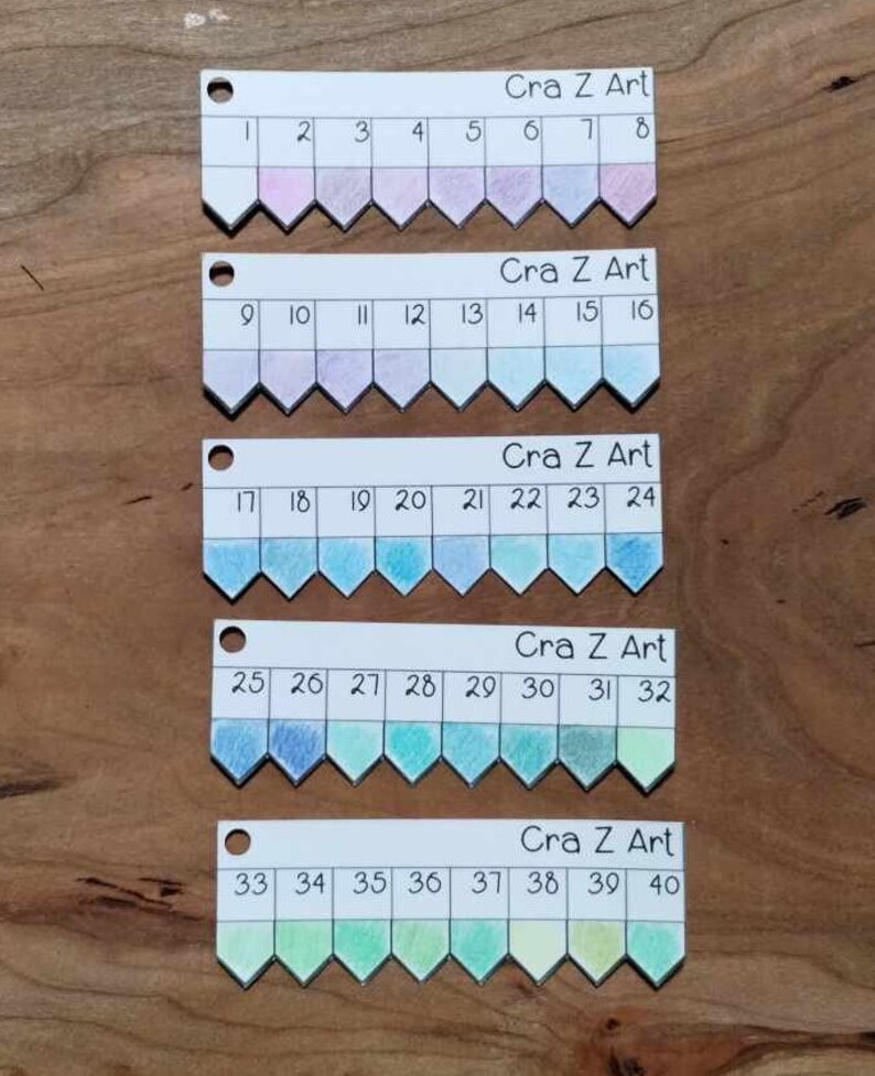 以下が含まれることがあります： 「Cra Z Art」とラベル付けされた、1から40までの番号が付けられた5行の色見本。各行には、ピンク、パープル、ブルー、グリーン、イエローのグラデーションで8つの色見本があります。