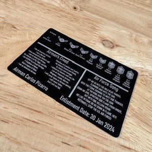 May include: A black and white Air Force enlistment card with the Airman's Creed, Air Force Song, and the text "Airman Carlos Pizarro" and "Enlistment Date: 30 Jan 2024".