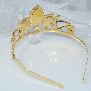 May include: A gold tiara with clear rhinestones. The tiara has a pointed crown and a headband.