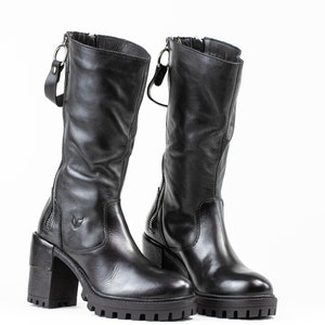 May include: A pair of black leather boots with a chunky heel and a zipper on the side. The boots have a slightly distressed look and are made of high-quality leather.