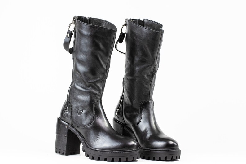 May include: A pair of black leather boots with a chunky heel and a zipper on the side. The boots have a slightly distressed look and are made of high-quality leather.