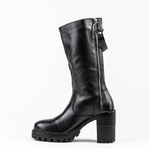 May include: Black leather knee-high boots with a chunky heel and a zipper up the back.