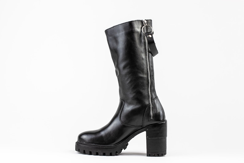 May include: Black leather knee-high boots with a chunky heel and a zipper up the back.