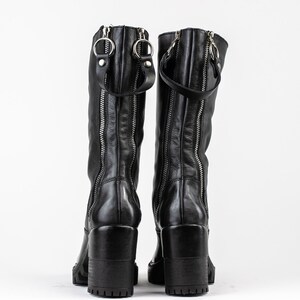May include: A pair of black leather knee-high boots with side zippers and a chunky heel.