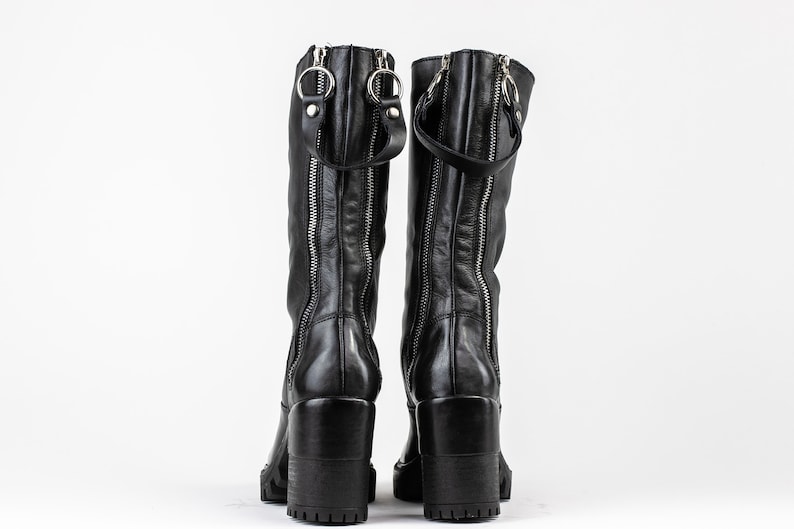 May include: A pair of black leather knee-high boots with side zippers and a chunky heel.