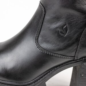 May include: Black leather ankle boots with a chunky heel and a side zipper. The boots have a small logo on the side.