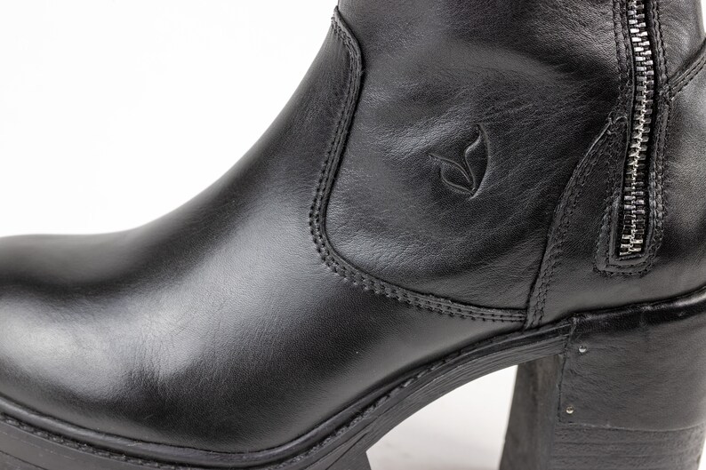 May include: Black leather ankle boots with a chunky heel and a side zipper. The boots have a small logo on the side.