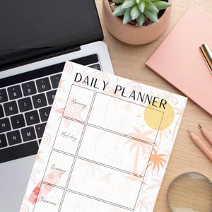 May include: A white daily planner with a tropical design, featuring palm trees and a sun graphic. The planner is open, displaying sections for morning, mid-day, evening, and tomorrow. A laptop, pencils, and a pink notepad with a gold clip are also visible.