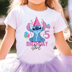 May include: A young girl wearing a white t-shirt with a cartoon character design, a purple tutu, and purple sunglasses. The shirt features the text "Birthday Girl" and the number "5". The background is blurred, suggesting an outdoor party setting.