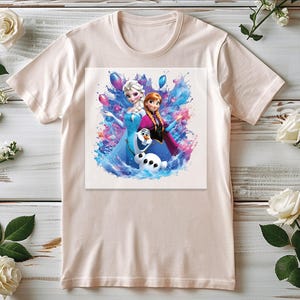 Puede incluir: Una camiseta de color beige claro con un gr&aacute;fico colorido de dos personajes femeninos animados y un mu&ntilde;eco de nieve. El gr&aacute;fico tiene un efecto de acuarela con tonos azules, rosas y morados. La camiseta es de material suave.