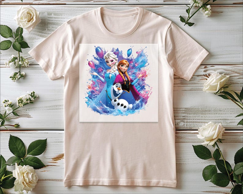 Puede incluir: Una camiseta de color beige claro con un gr&aacute;fico colorido de dos personajes femeninos animados y un mu&ntilde;eco de nieve. El gr&aacute;fico tiene un efecto de acuarela con tonos azules, rosas y morados. La camiseta es de material suave.