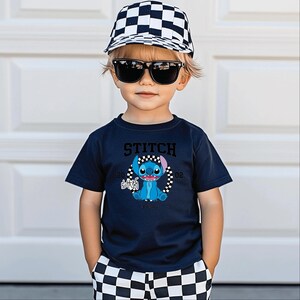 May include: A child wearing a navy blue t-shirt with a Stitch graphic, black sunglasses, and a black and white checkered baseball cap. The shirt features the word "STITCH" above the character and the year "2002". The child is also wearing black and white checkered shorts.