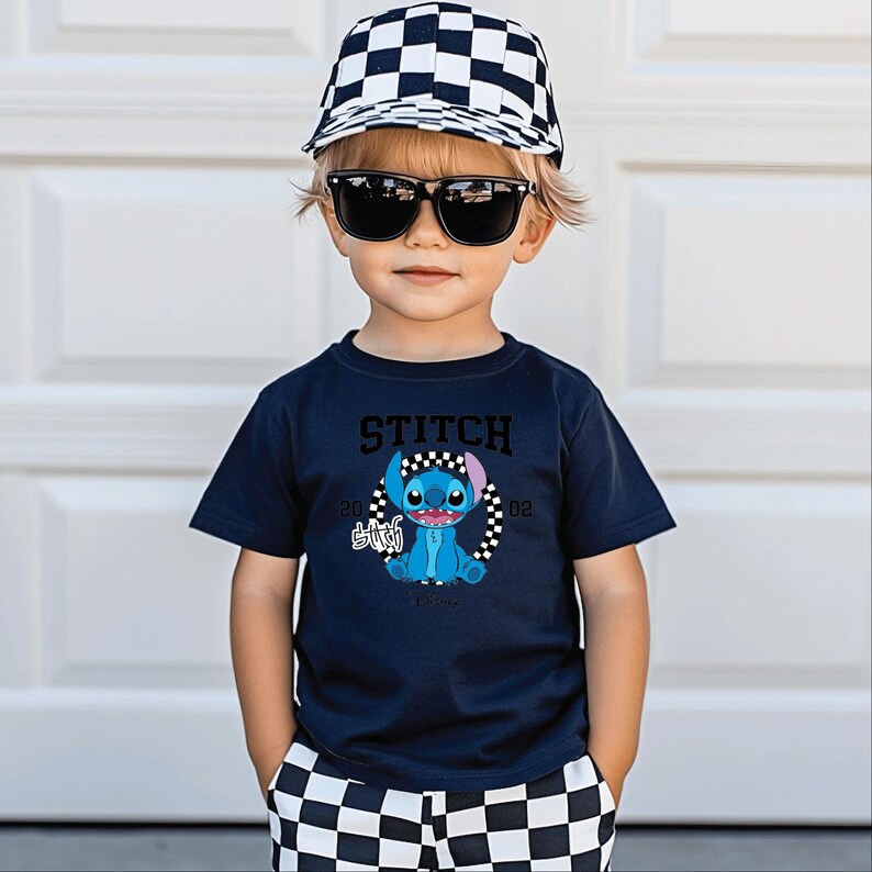May include: A child wearing a navy blue t-shirt with a Stitch graphic, black sunglasses, and a black and white checkered baseball cap. The shirt features the word "STITCH" above the character and the year "2002". The child is also wearing black and white checkered shorts.