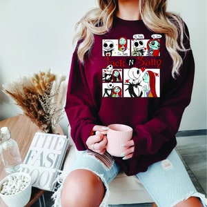 Puede incluir: Una sudadera granate con un gr&aacute;fico de Jack y Sally de Pesadilla antes de Navidad. El dise&ntilde;o incluye m&uacute;ltiples paneles con im&aacute;genes de los personajes y el texto "Jack N Sally".