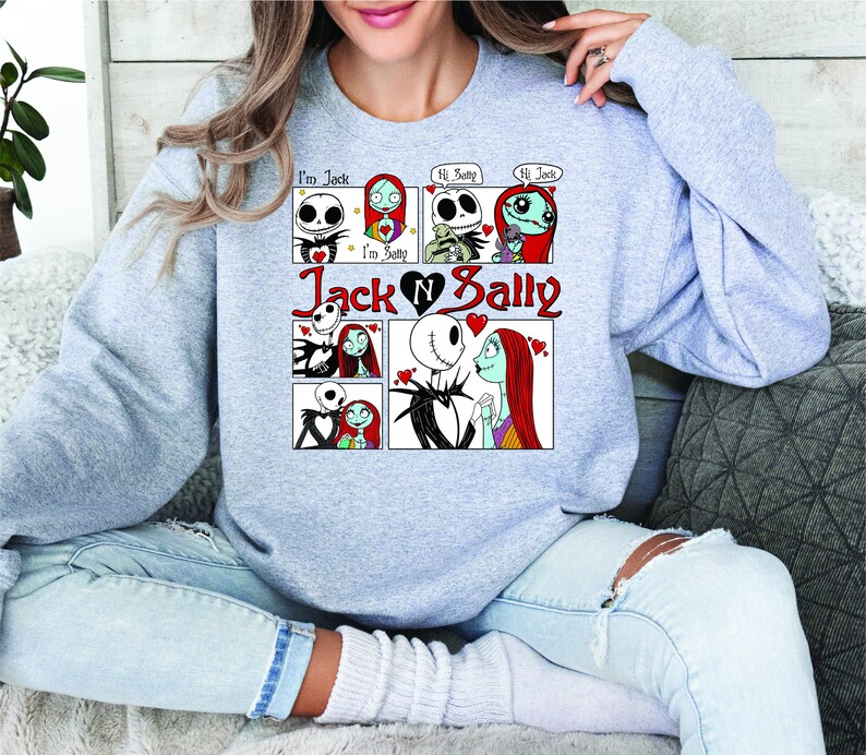 Puede incluir: Una sudadera gris claro con un dise&ntilde;o de c&oacute;mic de Jack y Sally de The Nightmare Before Christmas. El dise&ntilde;o incluye el texto "I'm Jack", "I'm Sally", "Jack N Sally" y bocadillos con "Hi Sally" y "Hi Jack".