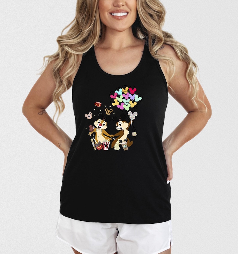 May include: Black tank top featuring a colorful graphic of Chip and Dale holding hands, surrounded by popcorn, drinks, and balloons. The cartoon characters are in a playful pose. The top is sleeveless and has a racerback design.