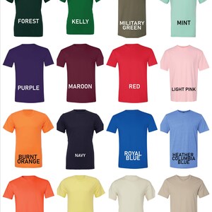 May include: A collection of short-sleeved t-shirts in various colors, including forest green, purple, and orange. Each shirt has a different color name printed below it in white text. The shirts are displayed on a white background.