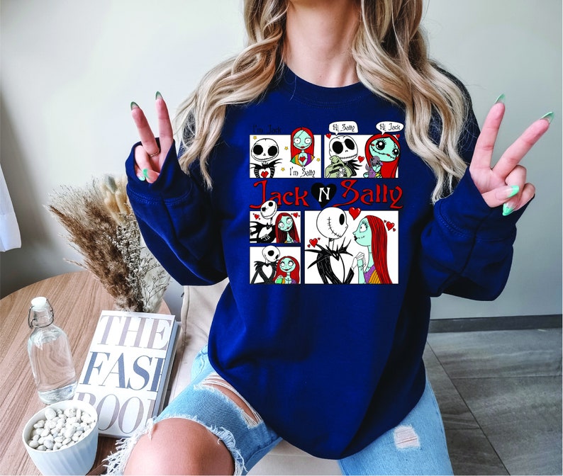 Puede incluir: Sudadera azul marino con un dise&ntilde;o gr&aacute;fico de Jack y Sally de The Nightmare Before Christmas. El dise&ntilde;o incluye m&uacute;ltiples paneles con im&aacute;genes de los personajes y el texto "Jack N Sally".