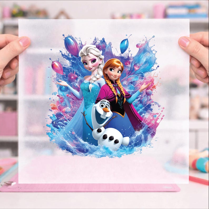 Puede incluir: Ilustraci&oacute;n colorida con personajes de la pel&iacute;cula animada "Frozen". Elsa, Anna y Olaf el mu&ntilde;eco de nieve se representan con salpicaduras de agua azul, rosa y morada, con esferas flotantes. La obra de arte est&aacute; sostenida por manos.