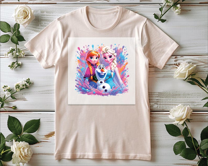 Pu&ograve; includere: Una maglietta beige chiaro con una grafica colorata dei personaggi animati Anna, Elsa e Olaf del film Frozen. Il design utilizza un effetto acquerello con spruzzi di rosa, blu e viola.