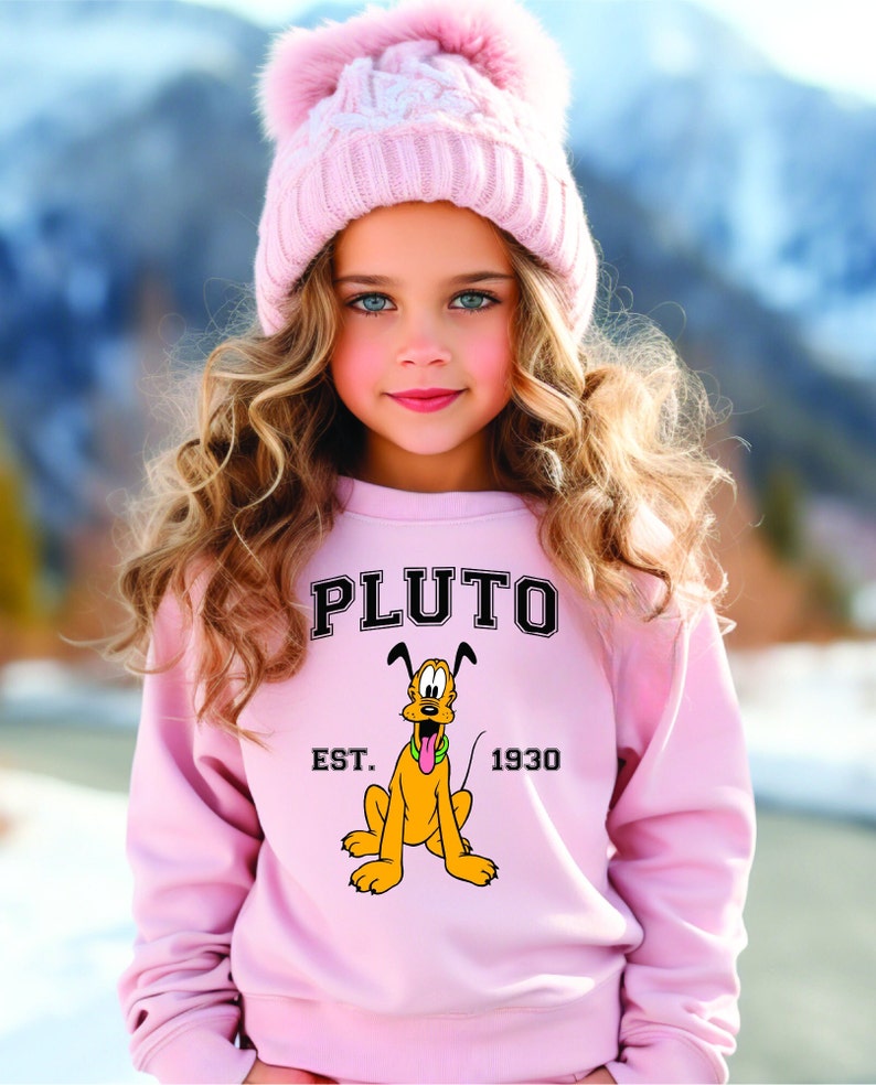 Puede incluir: Una sudadera rosa con una imagen de dibujos animados de Pluto, el perro de Disney, y el texto "PLUTO EST. 1930".