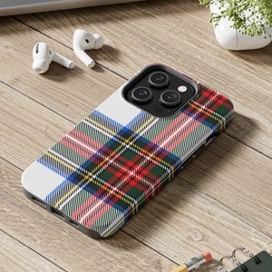 Puede incluir: Una funda de teléfono blanca con un patrón de cuadros rojos, verdes, azules y amarillos. La funda está diseñada para un teléfono inteligente con una protuberancia de cámara.