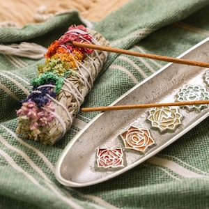 May include: A white sage smudge stick with colorful flowers and herbs, two brown incense sticks, and a silver tray with seven chakra symbols.
