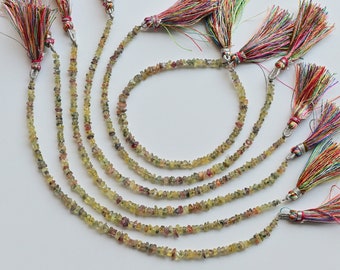 May include: A set of seven strands of green, yellow, and red gemstone beads with colorful tassels.